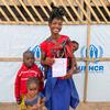 Une mère et ses trois enfants dans un centre de transit à Pweto, en République démocratique du Congo. Elle est contente de retourner chez elle.