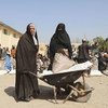 अफ़ग़ानिस्तान के हेरात में कुछ महिलाएँ, वितरण केंद्र से खाद्य राहत सामग्री ला रही हैं. (2021)