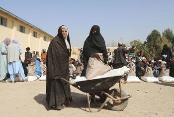 अफ़ग़ानिस्तान के हेरात में कुछ महिलाएँ, वितरण केंद्र से खाद्य राहत सामग्री ला रही हैं. (2021)