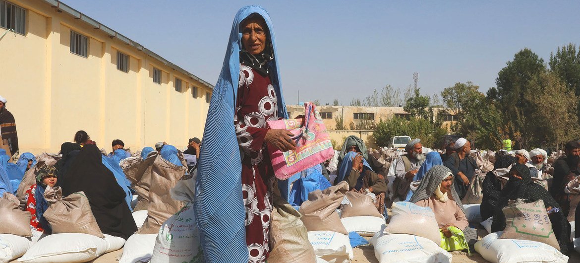 أشخاص يتلقون حصصا غذائية في أحد مواقع التوزيع التابعة لبرنامج الأغذية العالمي في ضواحي هرات في أفغانستان.