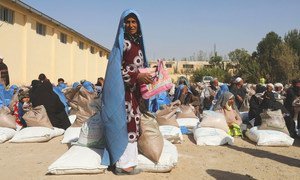 Des gens reçoivent des rations alimentaires à un site de distribution du PAM près d'Hérat, en Afghanistan.