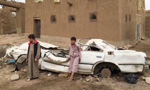 Young boys stand in front of a damaged vehicle in Sa'ada, Yemen.