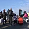 Familias transportando sus pertenencias por el paso fronterizo de Zosin, en Polonia, tras huir de Ucrania. 