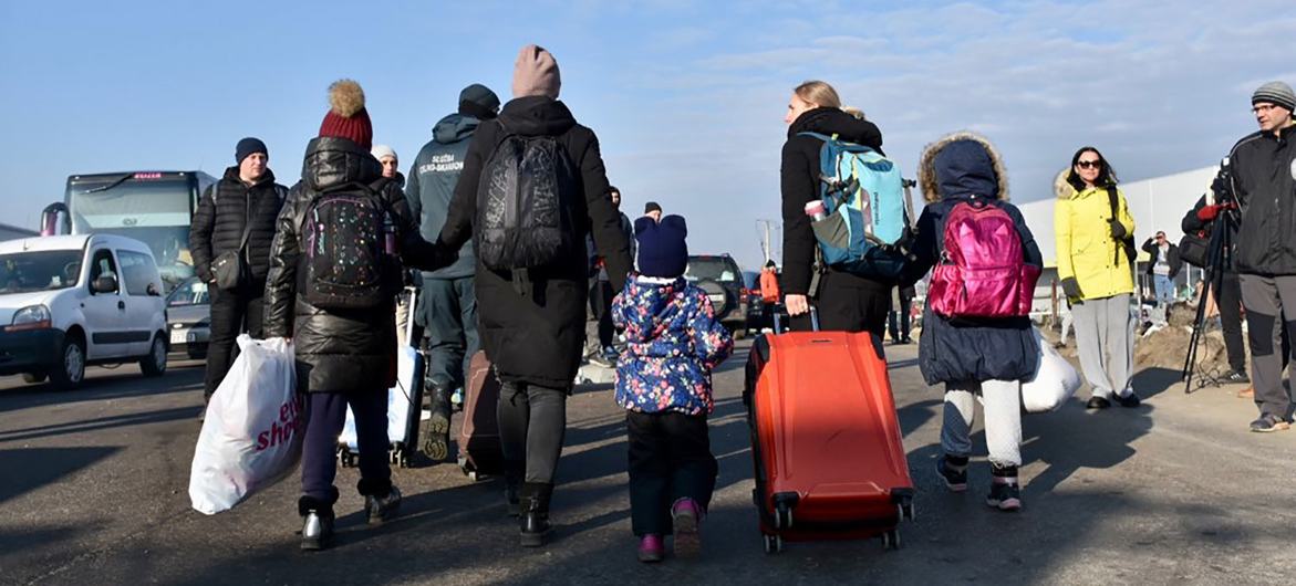 Famílias cruzam a fronteira com a Polônia após deixarem a Ucrânia. 