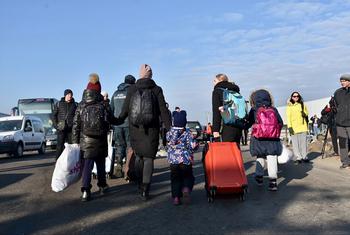 عائلات تحمل أمتعتها عبر معبر زوسين الحدودي في بولندا بعد الفرار من أوكرانيا.