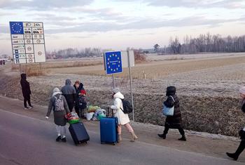 Des personnes franchissent la frontière entre l'Ukraine et la Pologne.