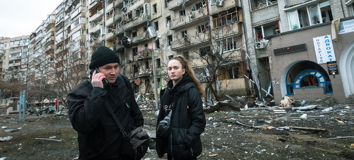 Le 25 février 2022 à Kiev, en Ukraine, un homme appelle de la famille, alors qu'il se trouve devant un immeuble endommagé par les opérations militaires.