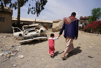 A man walks with his three-year-old daughter in the Harat Al-Masna'a slum in Sana'a, Yemen.