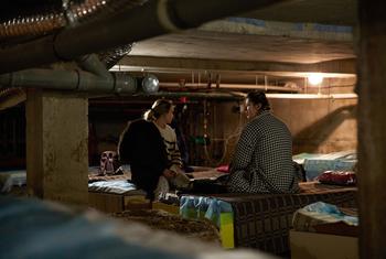 Deux femmes assisent sur des lits de fortune dans une cave en Ukraine.