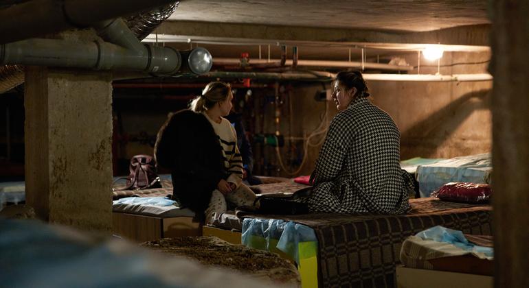 Two women sit on makeshift beds in the basement in Ukraine.