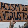 "Le racisme est aussi un virus", lit-on sur cette pancarte brandie lors d'une manifestation contre le racisme à Montréal, au Canada, en mars 2022.