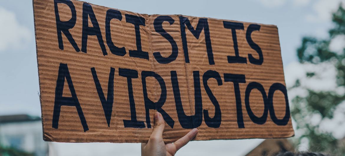 شخص يرفع علامة مكتوب عليها "العنصرية هي فيروس" خلال احتجاجات لحياة السود مهمة في مونتريال، كندا. 