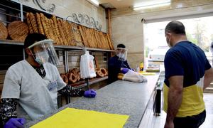 Shop workers sell bread at a bakery in Constantine, Algeria during the COVID-19 pandemic.