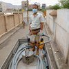 一名男子在一辆水车上工作，向也门萨那的社区供水。在新冠大流行期间，联合国儿童基金会为当地家庭提供清洁水。