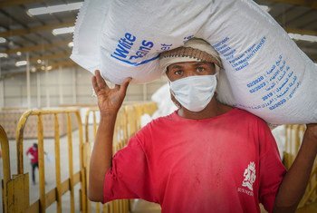 Trabajador humanitario carga un costal de frijol del almacén de distribución de comida del Programa Mundial de Alimentos en Sana´a, Yemen.