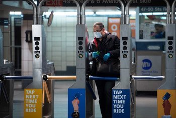 رجل يرتدي القناع والقفازات لدى مروره عبر أحد محطات القطار في مدينة نيويورك مع استمرار تفشي جائحة كوفيد-19.
