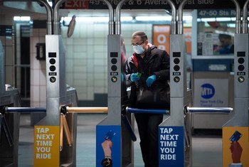 A man wears a mask and gloves as he enters the subway system during the Coronavirus (COVID-19) outbreak in New York City.