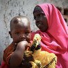 امرأة وطفلها الصغير ينتظران خارج عيادة طبية مجانية في كيسمايو ، الصومال.