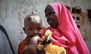 A women and her young child wait outside a free medical clinic in Kismayo, Somalia.