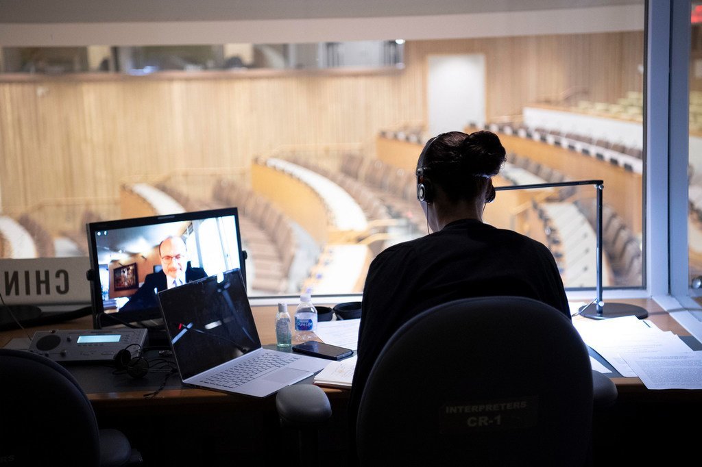一名口译员在联合国会议厅内进行同声传译，由于本场会议本身通过线上方式进行，她面前的会议厅内空无一人。