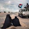 Soldados pasan al lado de dos mujeres limosneras en Lahj, Yemen.