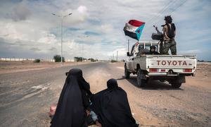 Soldiers drive at speed past two women begging in Lahj, Yemen.