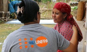 A UNFPA staff member speaks with a new mother cradling her child (not pictured), who were affected by the devastating 2015 earthquakes in Nepal. (file photo)