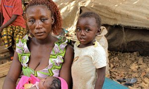 A refugee mother from Central African Republic sits with her children beside a makeshift shelter in Ndu village, the Democratic Republic of the Congo.