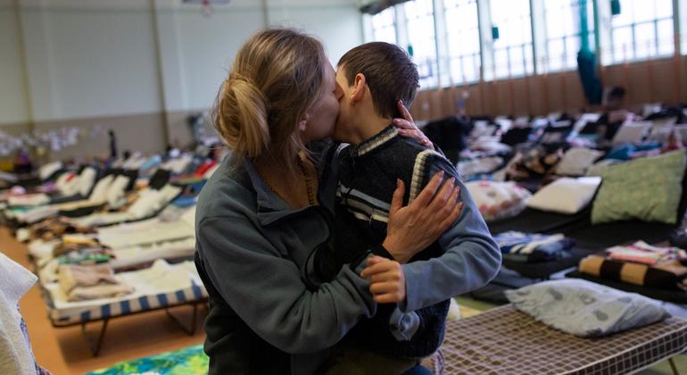 Refugiada da Ucrânia abraça filho em centro esportivo na Polônia que virou abrigo para refugiados. 