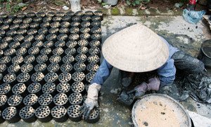 A woman  in Viet Nam makes environmentally-friendly biomass briquettes, a biofuel substitute to coal and charcoal cooking fuel.