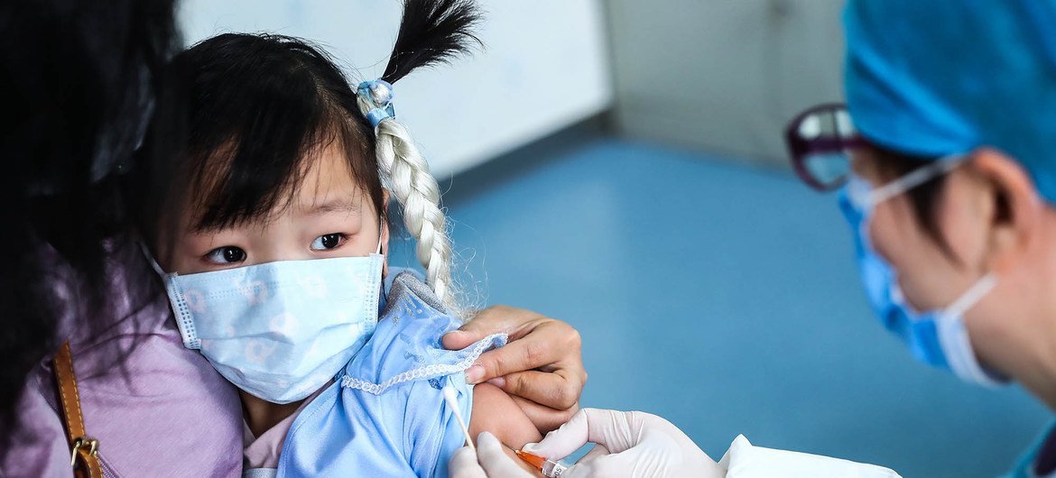 चीन की राजधानी बीजिंग के एक स्वास्थ्य केन्द्र में तीन साल की बच्ची को वैक्सीन दी जा रही है.