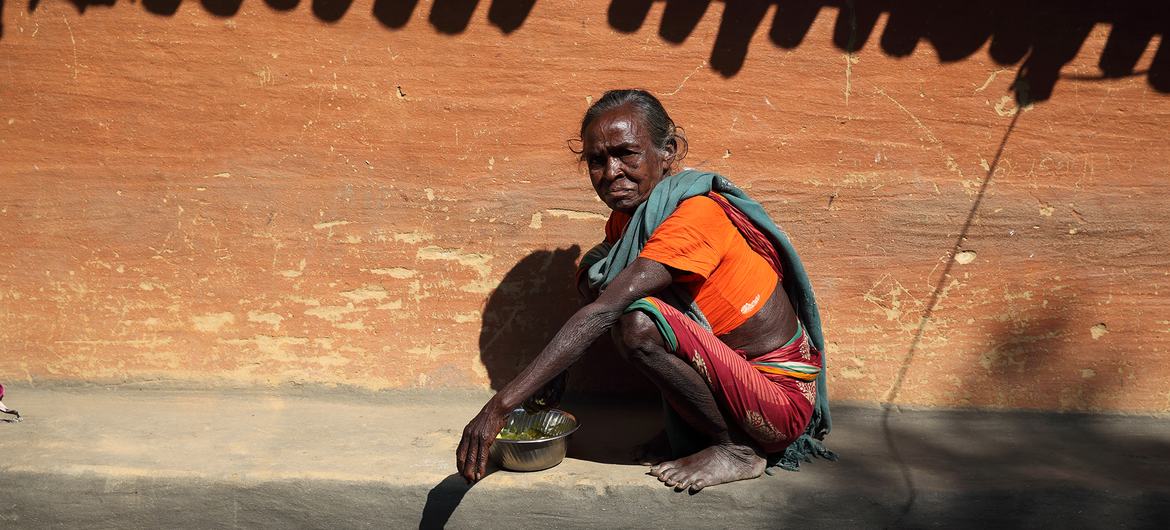 An elderly woman has her lunch in the sun at Adibasi Sahi, India. The extreme heat is impacting hundreds of millions of people in the country.