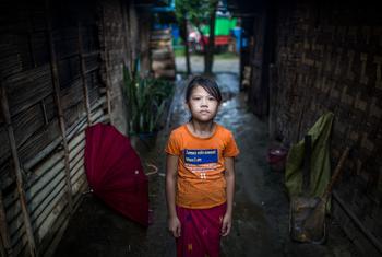म्याँमार में विस्थापितों के लिये बनाए गए एक शिविर में, अपने घर के बाहर खड़ी एक लड़की.