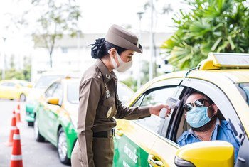 泰国曼谷，一位女警正在为出租车司机测量体温。