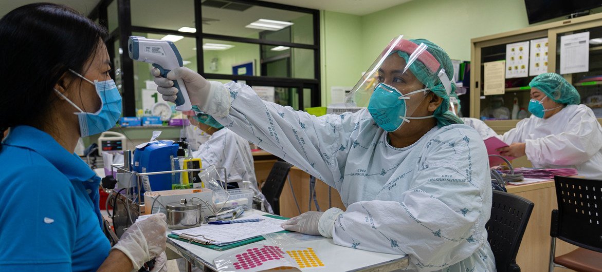 थाईलैण्ड के नोन्थाबुरी प्रांत में एक स्वास्थ्यकर्मी एक मरीज़ के तापमान की जाँच कर रही है.
