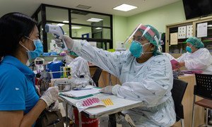 A healthcare worker checks the temperature of a patient at a hospital in Nonthaburi Province, Thailand.