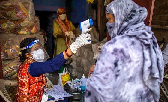 Vandana Gupta, a community worker with SEWA, checking body temperature as part of COVID-19 safety protocols at a ration distribution centre in Jahangir Puri, New Delhi, India. 