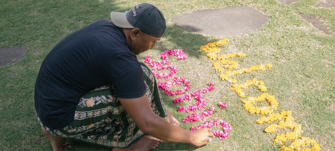 Dekha Dewandana arranges letters with flowers at Esa di Kubu Homestay in Sudaji Village, Buleleng, Bali, Indonesia.