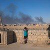 在伊拉克，由于伊黎伊斯兰国点燃的石油大火，孩子们从墙壁上看着燃烧的油井冒出的烟雾。