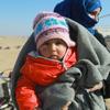 在叙利亚农村的一个非正式定居点，一对母亲和孩子在等待他们的冬季援助包。