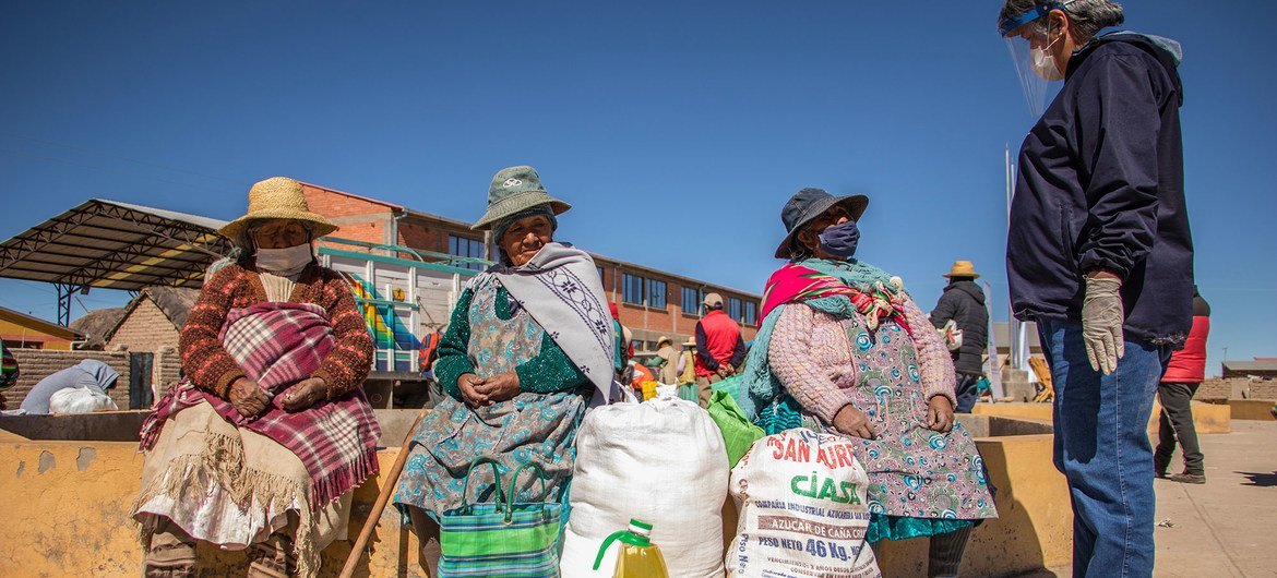 Un représentant du Programme alimentaire mondial (PAM) en Bolivie discute avec des femmes du groupe autochtone Uru-Murato des dangers de la Covid-19 et des pratiques nutritionnelles saines