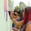 कोलम्बिया में महिलाएँ एक दीवार पर शान्ति सन्देश लिख रही हैं. 