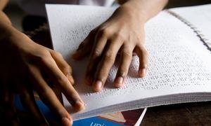 A thirteen-year-old boy reads by braille method at the academy where he lives in Kolkata, India.