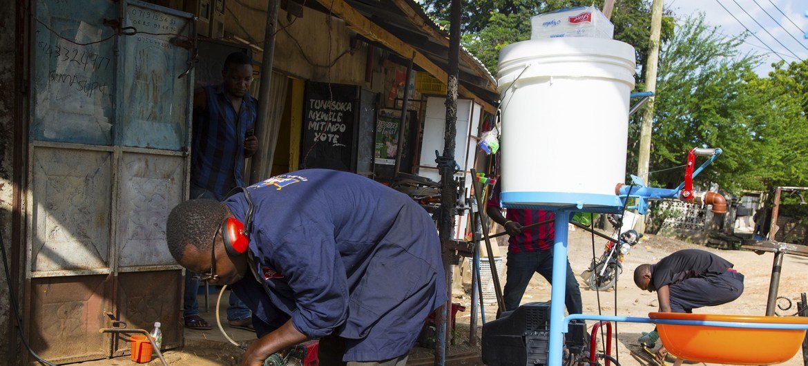 ورشة محلية في تنزانيا حيث يقوم العامال بصنع جهاز لغسل اليدين يمكن المرء بغسل اليدين دون لمس الصابون أو الصنبور.