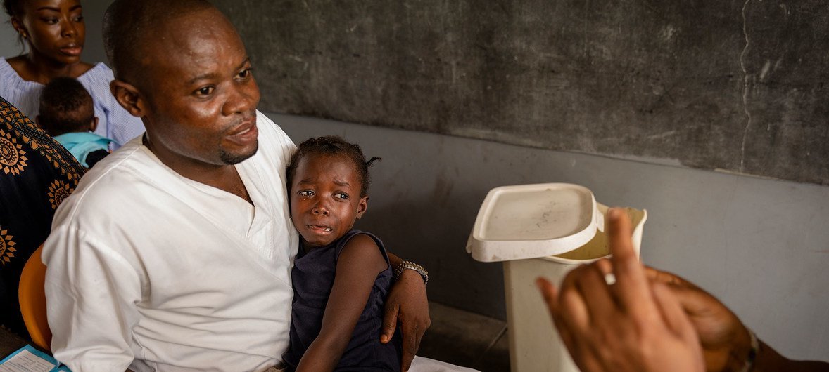 Una niña junto a su padre antes de recibir la vacuna contra el sarampión en la Républica Democrática del Congo.