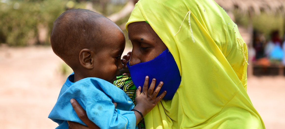 Un bebé juega con la máscara de su mamá en en un centro de apoyo nutricional en Bertoua, Camerún.