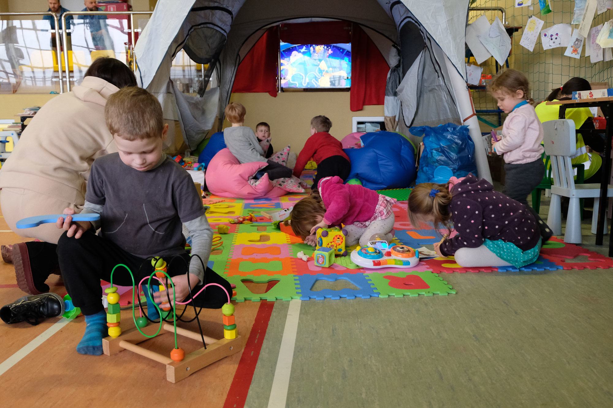 الأطفال يتعلمون ويلعبون في ركن من صالة ألعاب رياضية مدرسية أقيمت لاستضافة العائلات اللاجئة التي فرت من الحرب في أوكرانيا.
