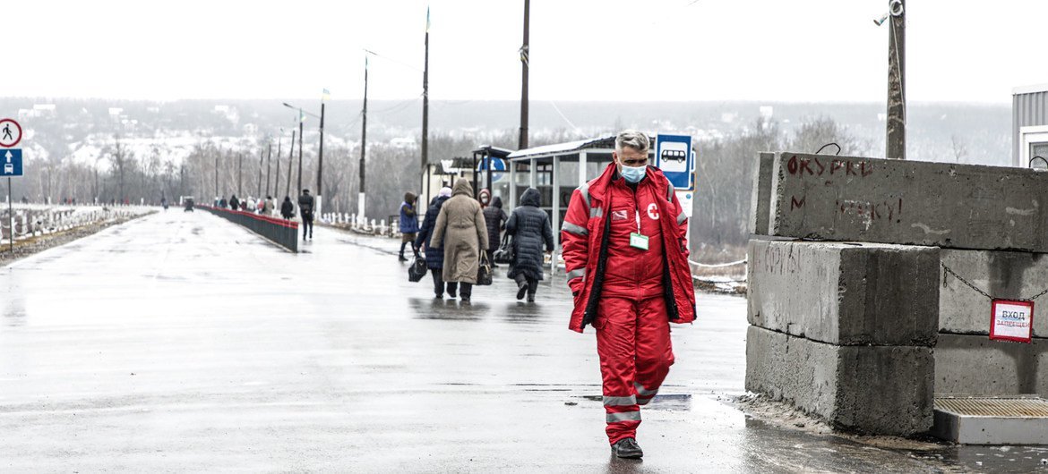 在乌克兰，一名医务人员走过正在进入政府控制区的当地人。