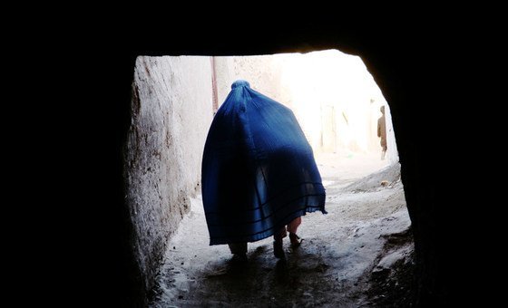  An Afghan woman covers a child under her Borqa while passing through a tunnel in Herat, Afghanistan.