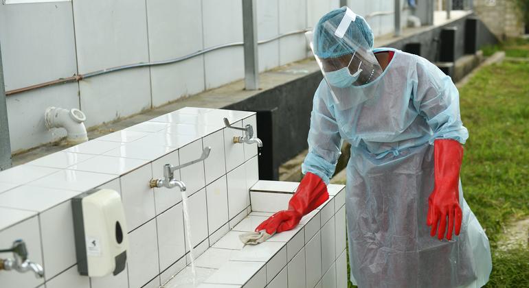 Um profissional de saúde desinfeta uma instalação externa de lavagem de mãos em um centro de tratamento de emergência em Kameza, Malawi